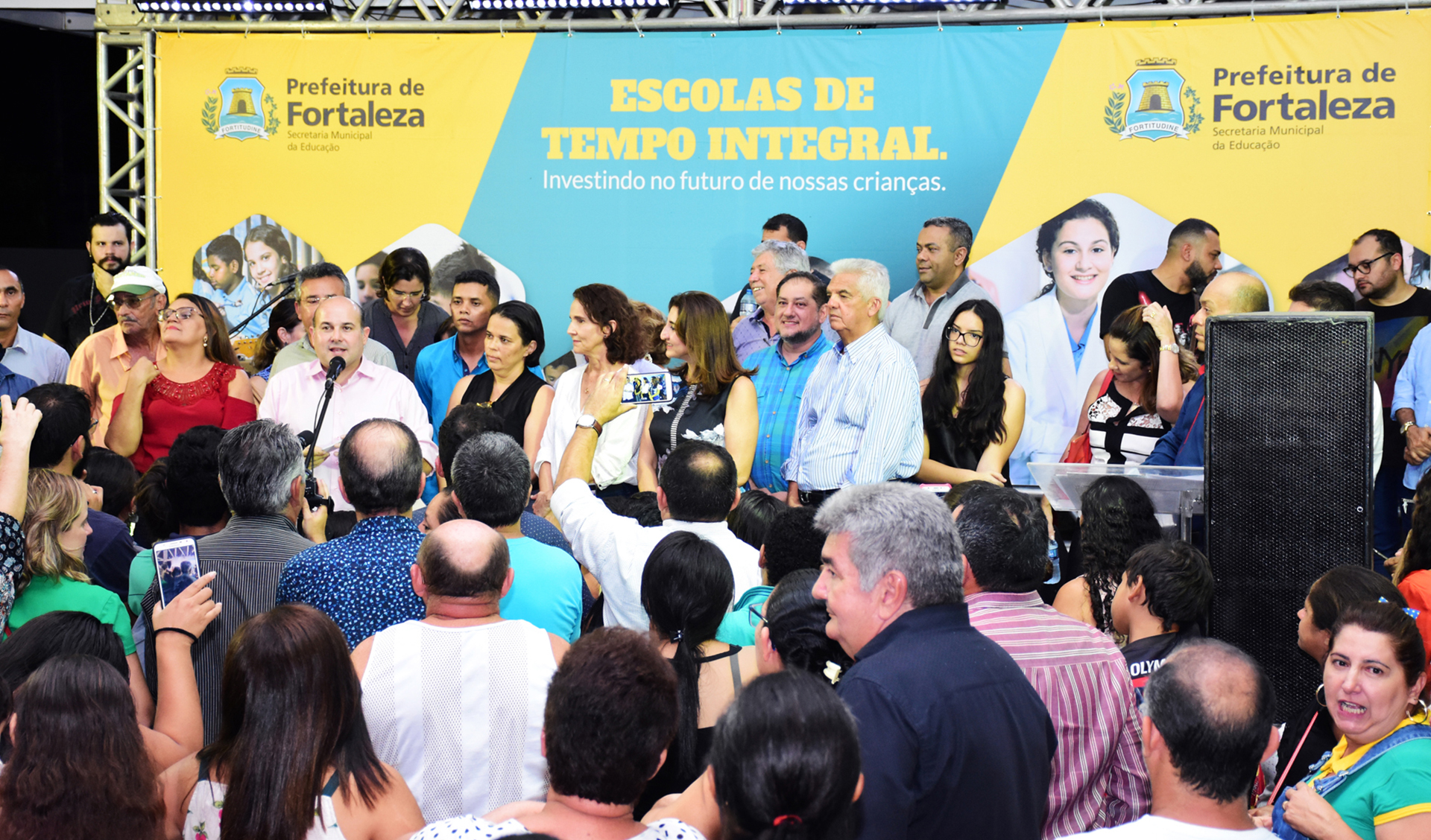prefeito roberto claudio discursa num palco, rodeado de dezenas de pessoas